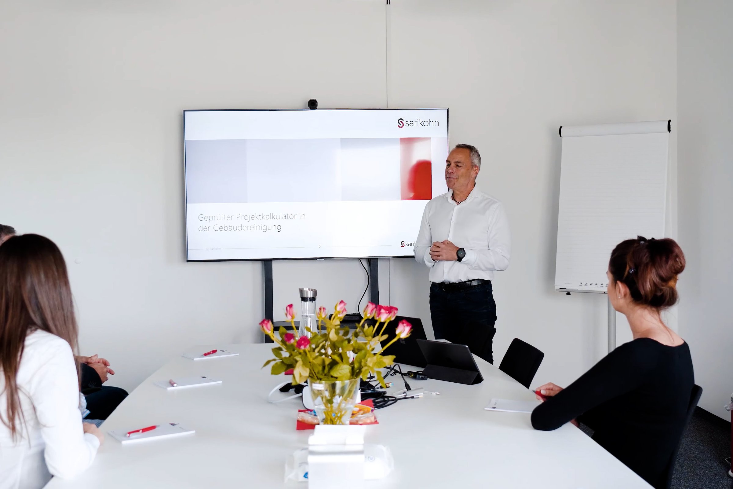 Seminar zur Projektkalkulation: Vortrag vor der Titelfolie des Lehrgangs, Teilnehmende am Tisch